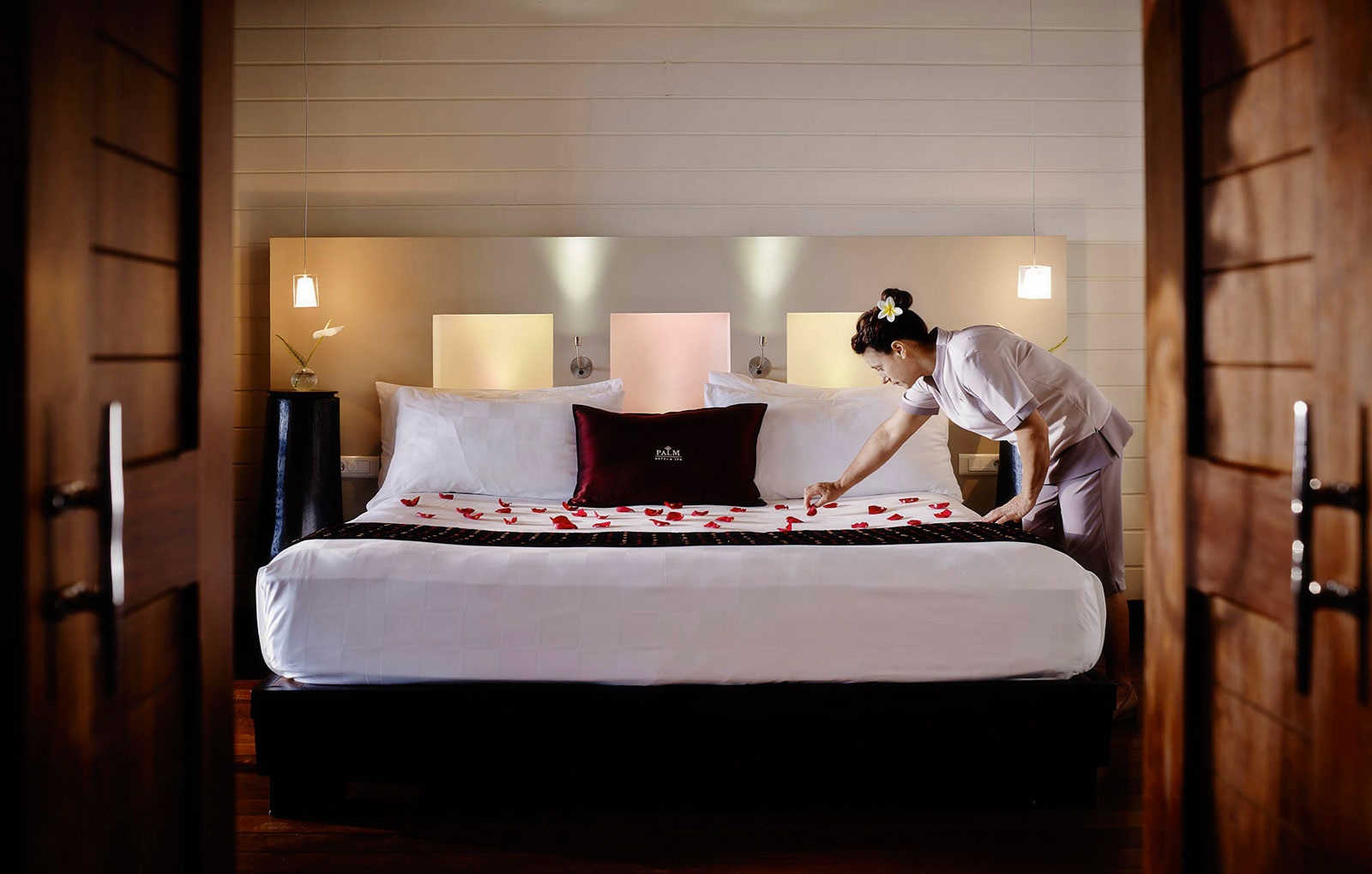 Hotel room with one bed and a house keeper placing rose petal