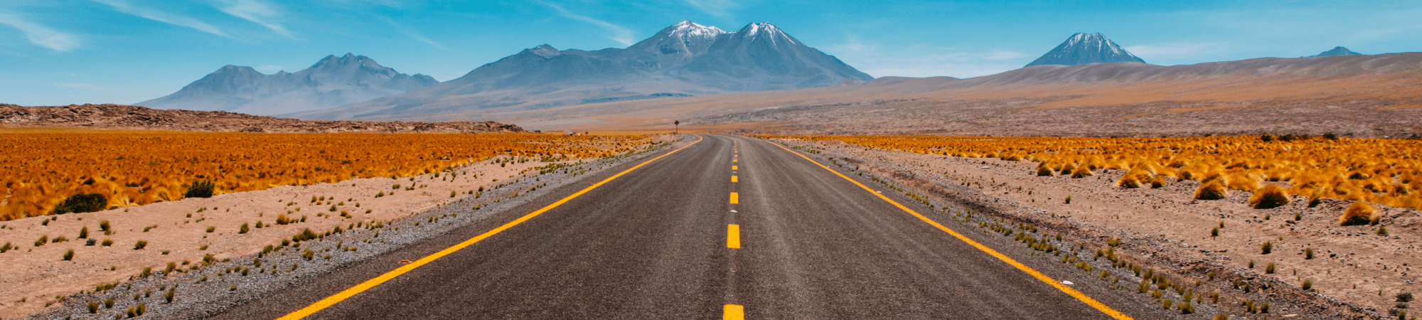 Empty highway road in a desert with a mountain in the distance