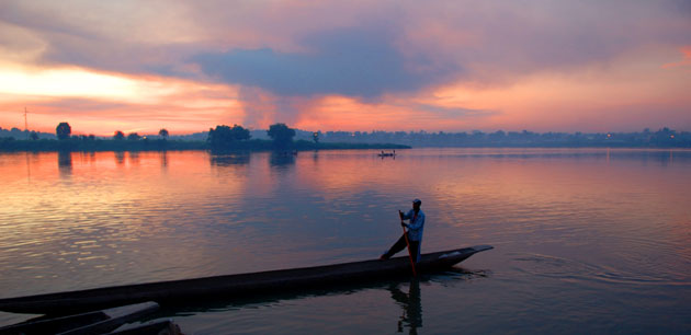 A man paddling a boat at sunset - Cultural Tour of Gabon & Democratic Republic of Congo