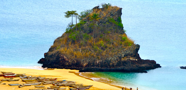 A rocky cliff connected to a beach that has boats on the sand - Tour of Equatorial Guinea