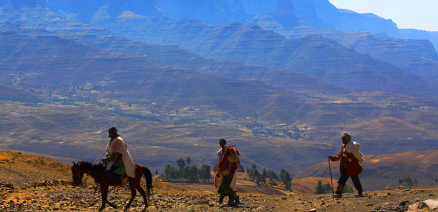 Men hiking by a large mountain - Ethiopian Highlights