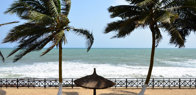 View of the ocean from a balcony with palm trees and umbrellas