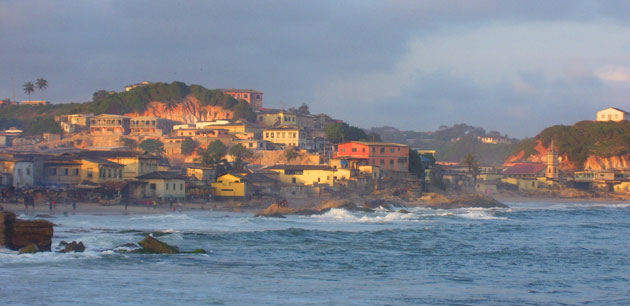 View of colorful houses next to a rocky shoreline