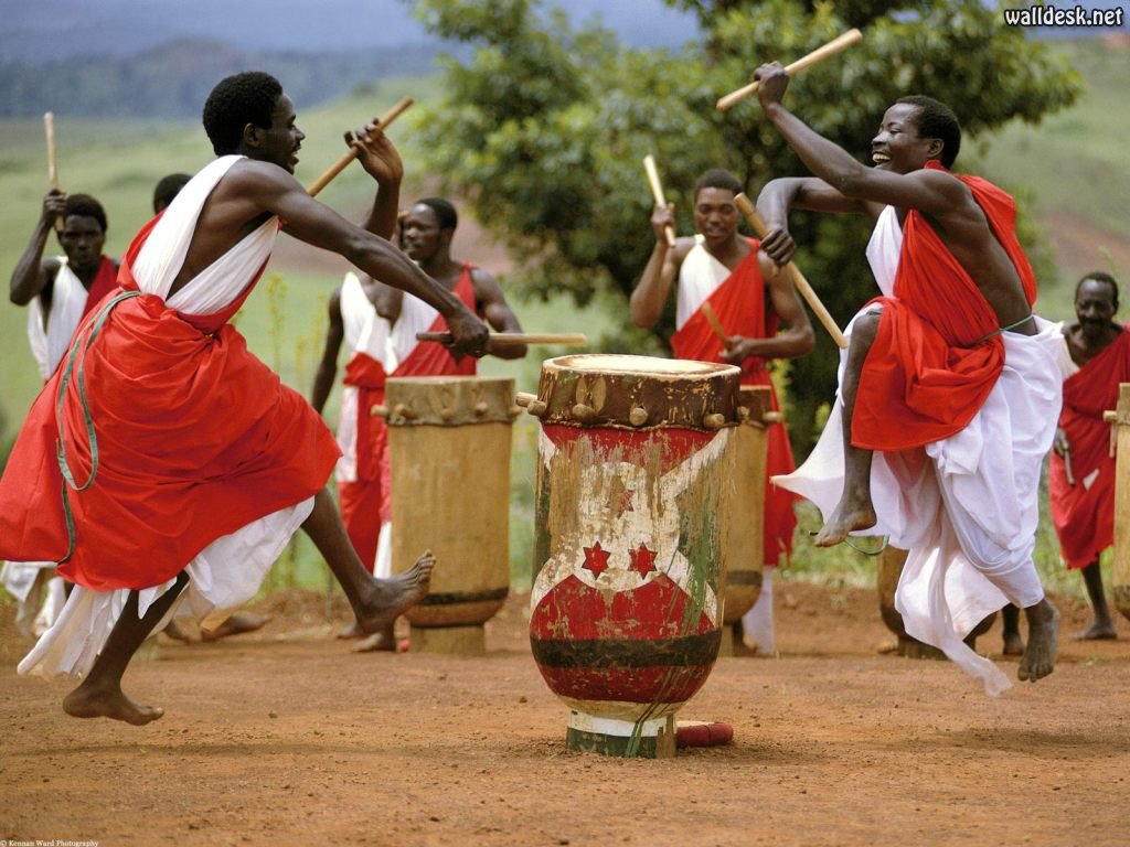 Men dressed in white and red robes banging drums