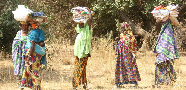 Women wearing colorful clothing carrying blankets on their heads
