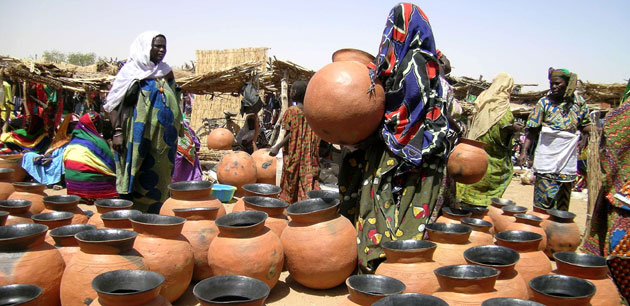 Women in colorful clothing walking around pots