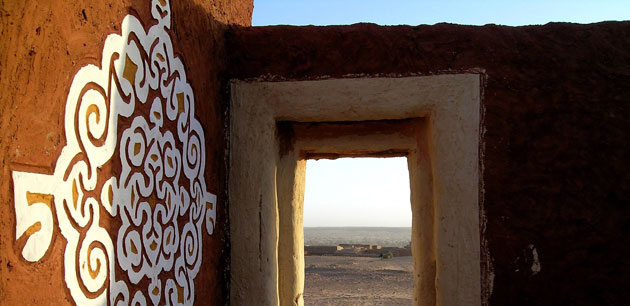 Entrance to a roofless area next to a building with a large white decoration - Explore Mauritania