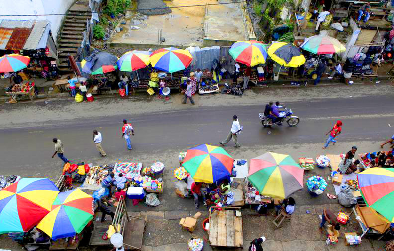 An outdoor market covered with colorful umbrellas with people walking through it