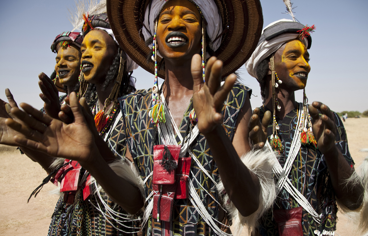 Women adorn with extravagant accessories with orange face paint
