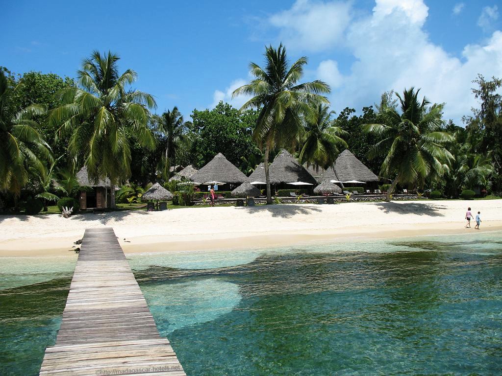 A pier leading to the beach with small buildings and bright blue water - Island Hopping Tour of Madagascar